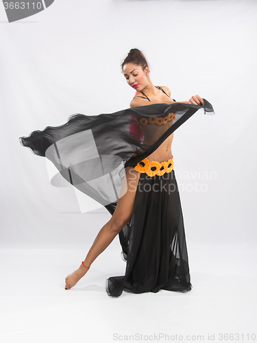 Image of Young girl mulatto dancing in a long black dress candid