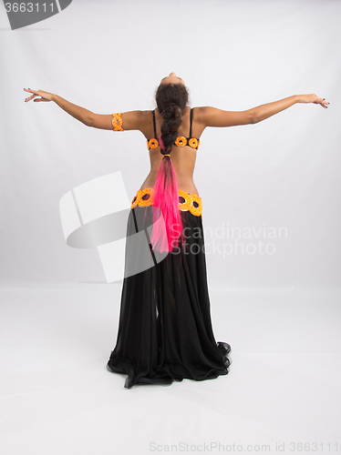 Image of Young girl mulatto dancing in a long black dress candid