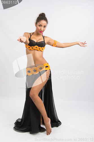 Image of Young girl mulatto dancing in a long black dress candid