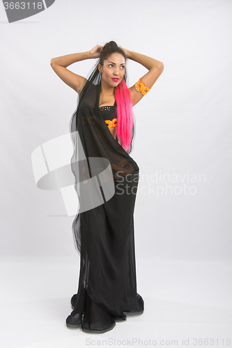 Image of Young girl mulatto dancing in a long black dress candid