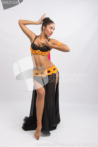 Image of Young girl mulatto dancing in a long black dress candid