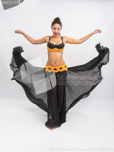 Image of Young girl mulatto dancing in a long black dress candid