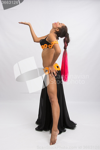 Image of Young girl mulatto dancing in a long black dress candid