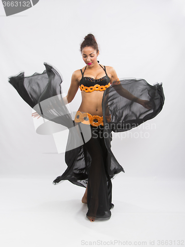Image of Young girl mulatto dancing in a long black dress candid
