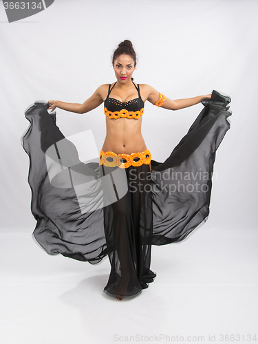 Image of Young girl mulatto dancing in a long black dress candid