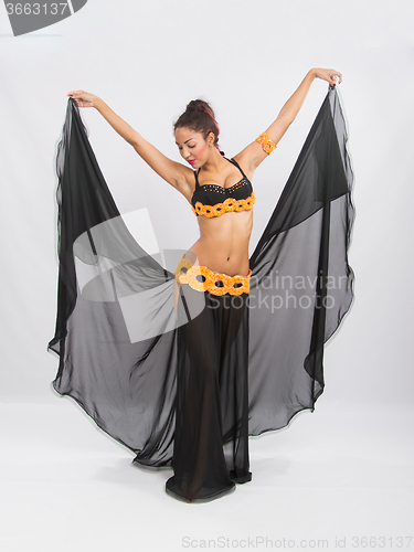 Image of Young girl mulatto dancing in a long black dress candid