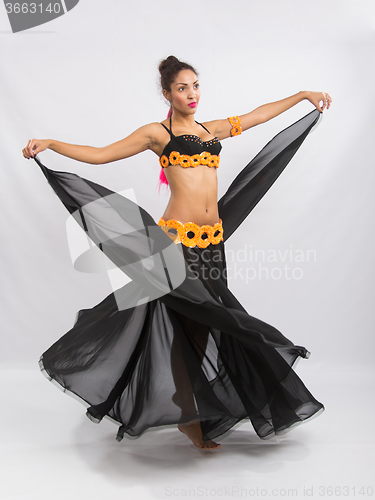 Image of Young girl mulatto dancing in a long black dress candid