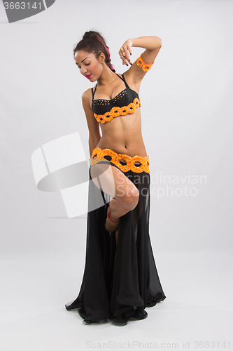 Image of Young girl mulatto dancing in a long black dress candid