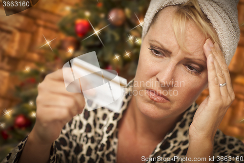 Image of Upset Woman Holding Credit Card In Front of Christmas Tree