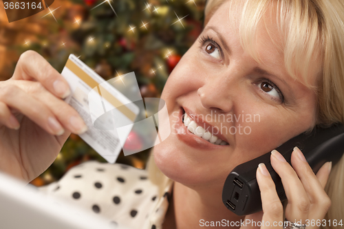 Image of Phone Holding Woman Credit Card In Front of Christmas Tree