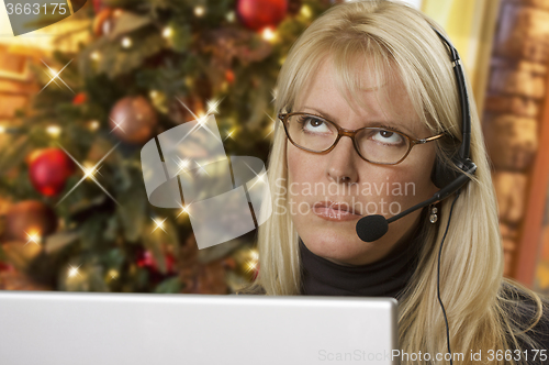 Image of Upset Woman with Headset In Front of Christmas Tree and Computer