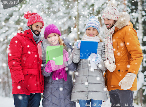 Image of smiling friends with tablet pc in winter forest