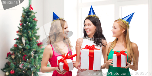 Image of smiling women in party caps with gift boxes