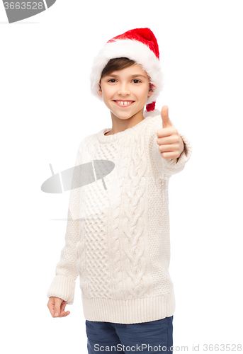 Image of smiling happy boy in santa hat showing thumbs up