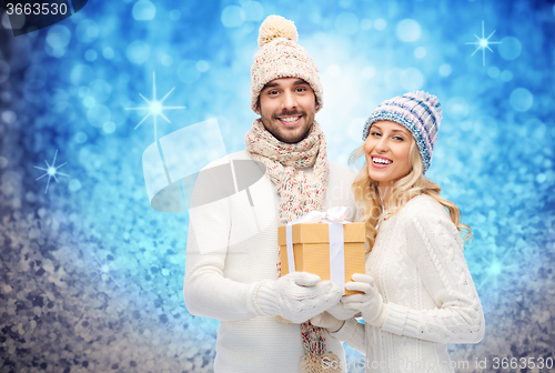 Image of smiling couple in winter clothes with gift box