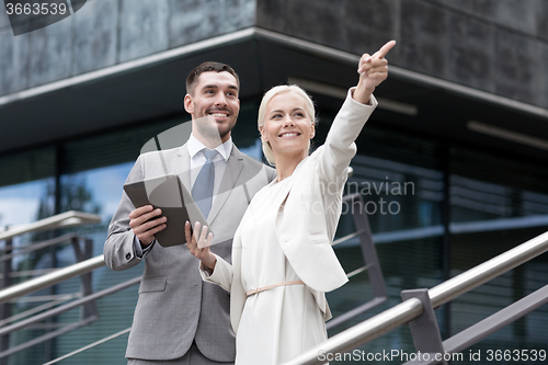 Image of smiling businessmen with tablet pc outdoors