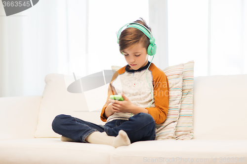 Image of boy with smartphone and headphones at home
