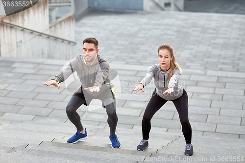 Image of couple doing squats and exercising outdoors