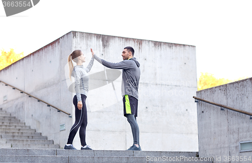 Image of happy couple giving high five outdoors