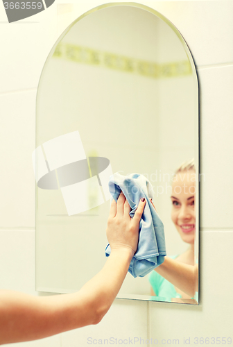 Image of close up of happy woman cleaning mirror with rag