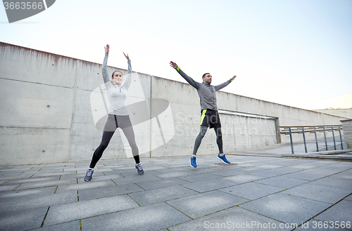 Image of happy man and woman jumping outdoors