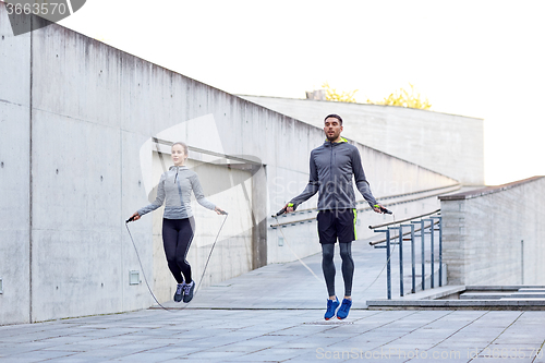 Image of man and woman exercising with jump-rope outdoors