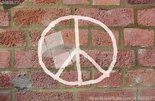 Image of peace sign drawing on red brick wall