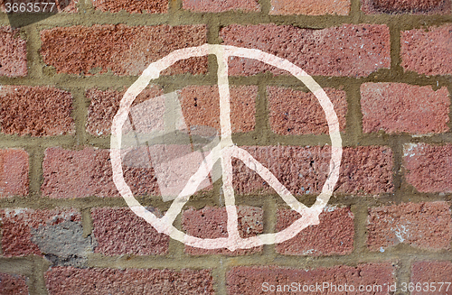 Image of peace sign drawing on red brick wall