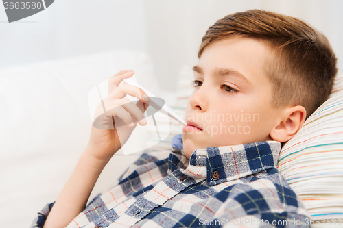 Image of ill boy with flu and thermometer at home