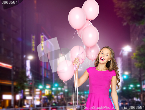 Image of happy young woman with balloons over night city