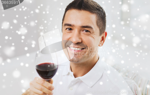 Image of happy man drinking red wine from glass at home