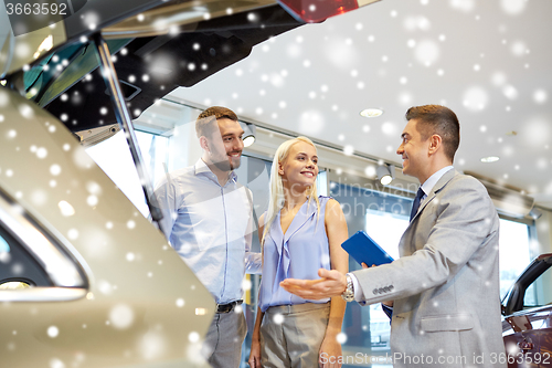Image of happy couple with car dealer in auto show or salon