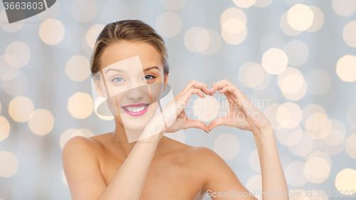 Image of smiling young woman showing heart shape hand sign