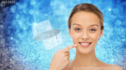 Image of happy young woman pointing finger to her teeth