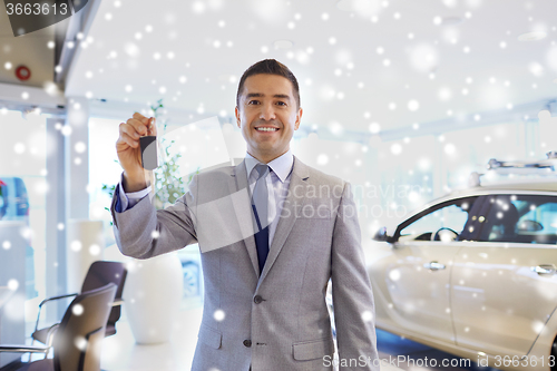 Image of happy man showing key at auto show or car salon