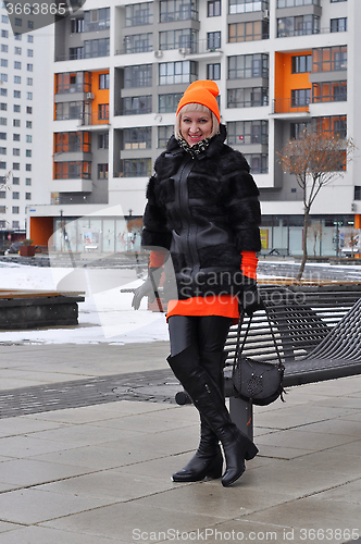 Image of The woman in a fur coat costs against new buildings