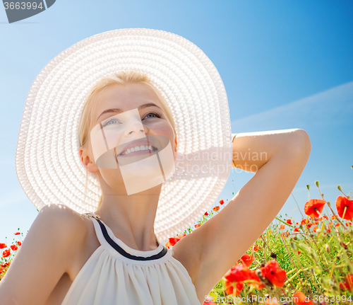 Image of smiling young woman in straw hat on poppy field