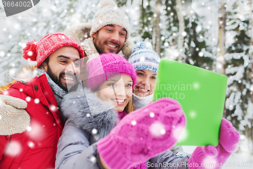 Image of smiling friends with tablet pc in winter forest