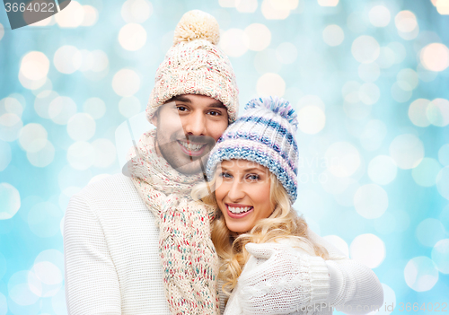 Image of happy couple in winter clothes hugging over lights