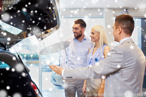Image of happy couple with car dealer in auto show or salon