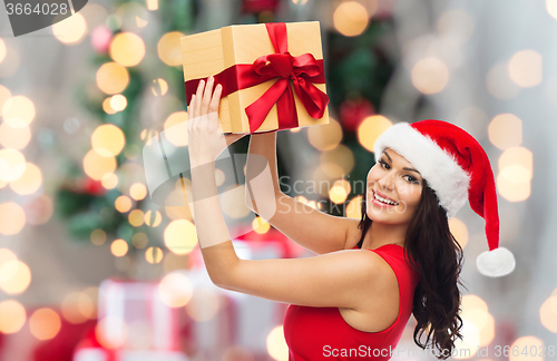Image of happy woman in santa hat with gift over lights