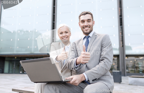 Image of smiling businesspeople with laptop outdoors