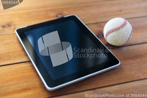 Image of close up of baseball ball and tablet pc on wood