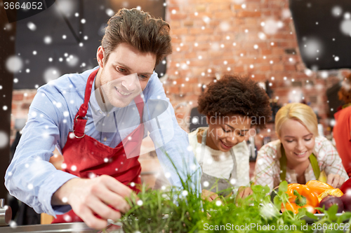 Image of happy friends cooking and decorating dishes