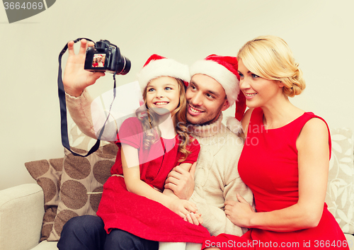 Image of smiling family in santa helper hats taking picture