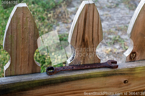 Image of old rusty wrench on fence