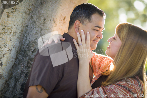 Image of Mixed Race Couple Leaning Against Tree In a Romantic Moment