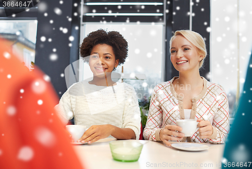 Image of happy young women drinking tea or coffee at cafe