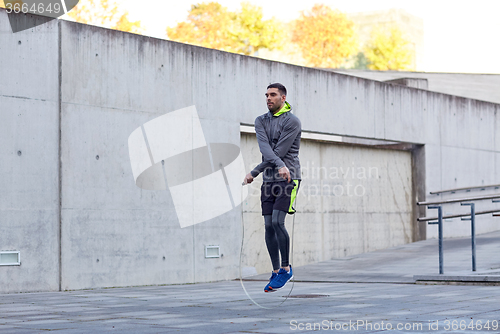 Image of man exercising with jump-rope outdoors