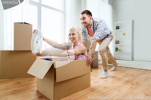 Image of couple with cardboard boxes having fun at new home